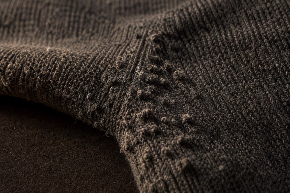 Real pilling on the underarm of a charcoal wool sweater